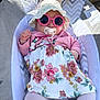 baby, child, sunglasses, pacifier, hat, dress, floral, pink, cardigan, tights, toy, seat, cushion, outdoor, sunlight, person, cute, fashion, infant, relaxing