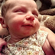 Bellefyre is registered to the contest to win money with this photo: baby, sleeping, smile, floral_clothing, blanket, infant, closeup, peaceful, soft_texture, cute, newborn, face, skin, person, relaxation, rest, comfort, child, portrait, warm