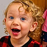 toddler, child, curly_hair, blue_eyes, red_checkered_clothing, indoor, portrait, happy, excited, face, person, smiling, young_child, expression, cute, curly_blonde_hair, background, wooden_door, clothing, people