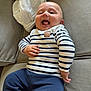 Ezeckiel participe au concours pour gagner de l'argent avec cette photo : baby, child, smiling, striped_shirt, navy_pants, couch, blanket, happy, infant, cute, indoor, portrait, face, hand, person, seated, clothing, cozy, skin, expression