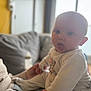Ezeckiel a rejoint le concours — aidez-le/la à gagner de superbes lots ! baby, infant, child, couch, sofa, hand, person, indoors, clothing, cute, expression, face, wide_eyes, cozy, blurred_background, animal_print, sitting, light, warm, home