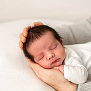 Freddie is registered to the contest to win money with this photo: newborn, baby, sleeping, hands, adult_hand, gentle, white_clothing, soft_texture, portrait, closeup, peaceful, infant, skin, person, rest, cozy, tenderness, family, love, care