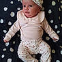 baby, infant, child, pink_clothing, hat, headwear, patterned_pants, floral, blanket, dots, cute, portrait, lying_down, small_hands, soft_fabric, white, black, looking_away, indoors, newborn
