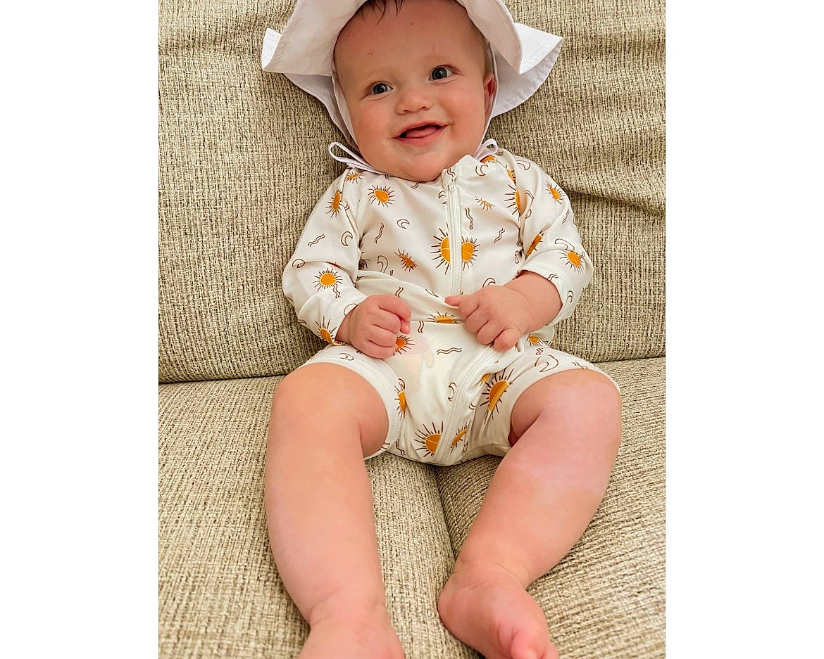 Anakin is registered to the contest to win money with this photo: baby, baby_toddler_clothing, child, collar, comfort, costume_hat, face, fashion_accessory, foot, happy, head, human_leg, joy, knee, pattern, person, sitting, skin, sleeve, smile