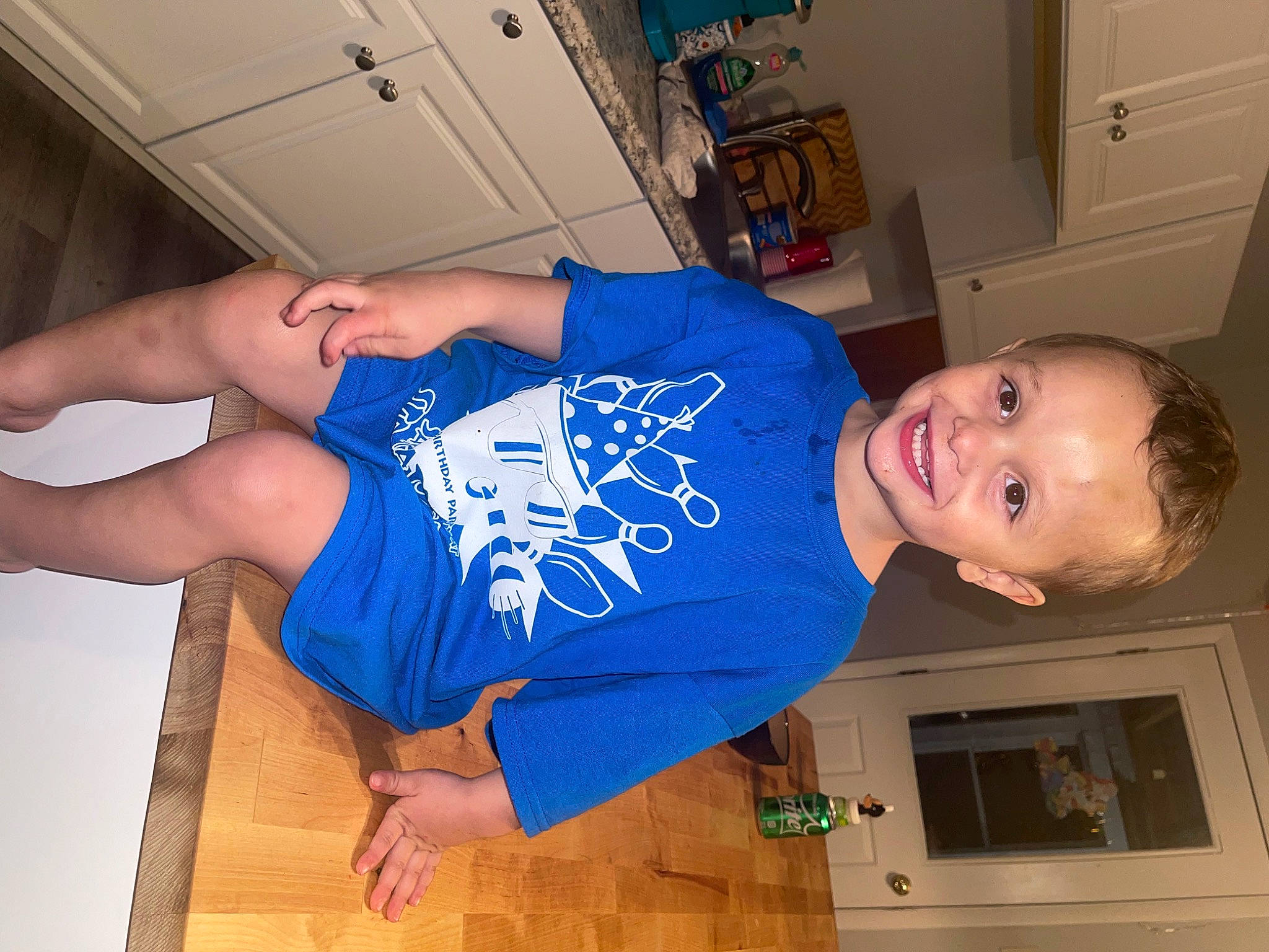 Mason is registered to the contest to win money with this photo: arm, baby_toddler_clothing, blue, cabinetry, child, elbow, electric_blue, fun, gesture, happy, human_leg, joy, knee, person, room, sleeve, smile, t_shirt, thigh, thumb