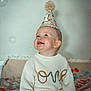 baby, child, party_hat, sweater, confetti, bubbles, smiling, happy, indoor, celebration, cute, portrait, sitting, cozy, festive, pom_pom, blanket, decorations, playful, joyful