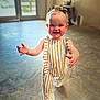 toddler, child, smiling, walking, indoor, striped_overalls, headband, baby, happy, person, floor, light, shadow, blurry_background, cute, portrait, young_child, clothing, fashion, playful