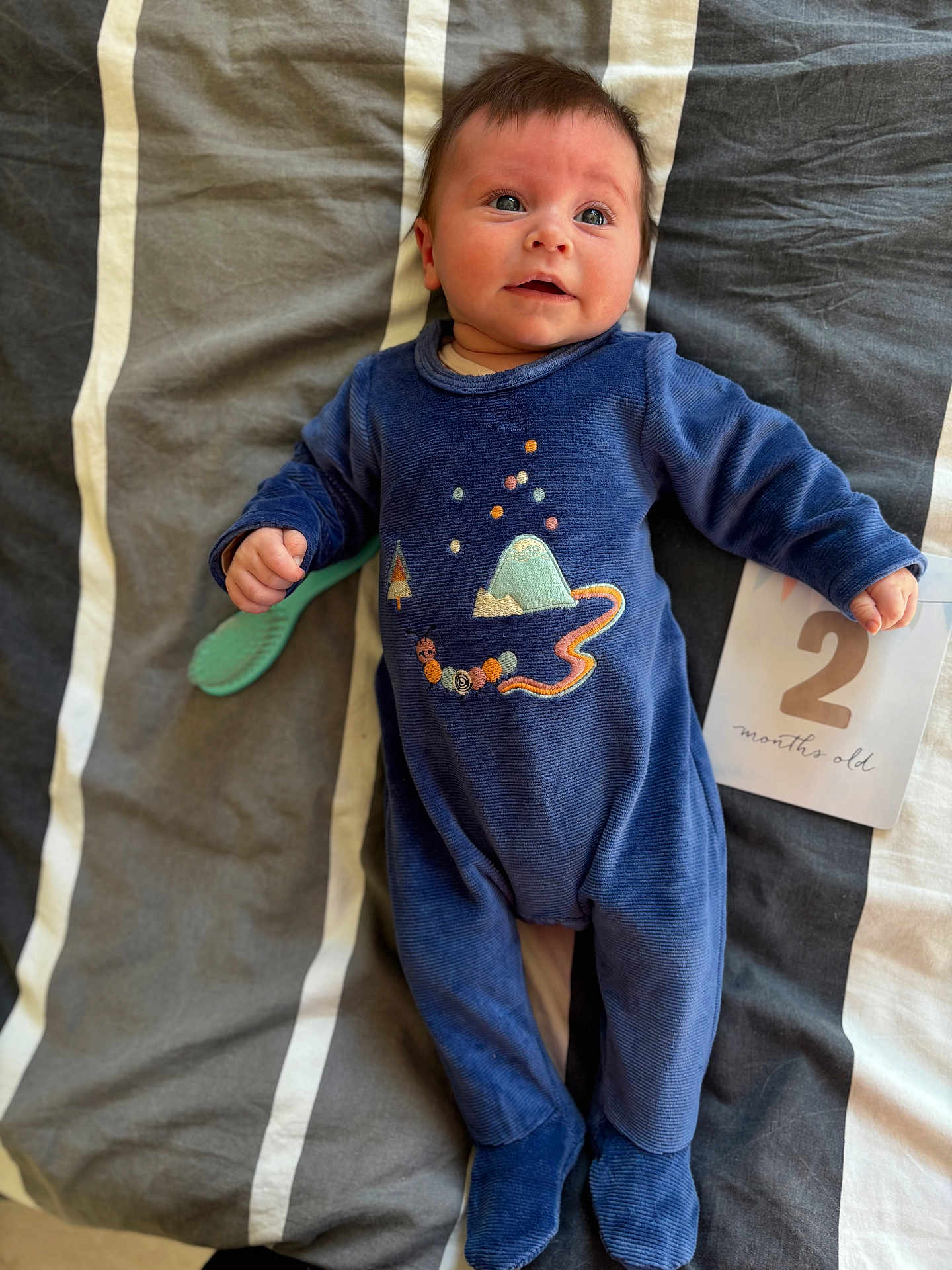 Jade participe au concours pour gagner de l'argent avec cette photo : baby, infant, blue_onesie, bedspread, striped_bedspread, milestone_card, 2_months_old, lying_down, brush, cute, child, person, portrait, indoors, soft_lighting, happy, newborn, smiling, face, clothing