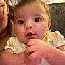 Wrenlee is registered to the contest to win money with this photo: baby, infant, child, face, portrait, sitting, indoor, sofa, adult, parent, hand, fingers, white_clothing, yellow_pattern, curious, looking_at_camera, close_up, home, cozy, photograph