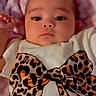 baby, infant, face, eyes, clothing, shirt, bow, pattern, leopard_print, blanket, pink, white, chevron, hand, soft, lying_down, portrait, cute, child, indoors