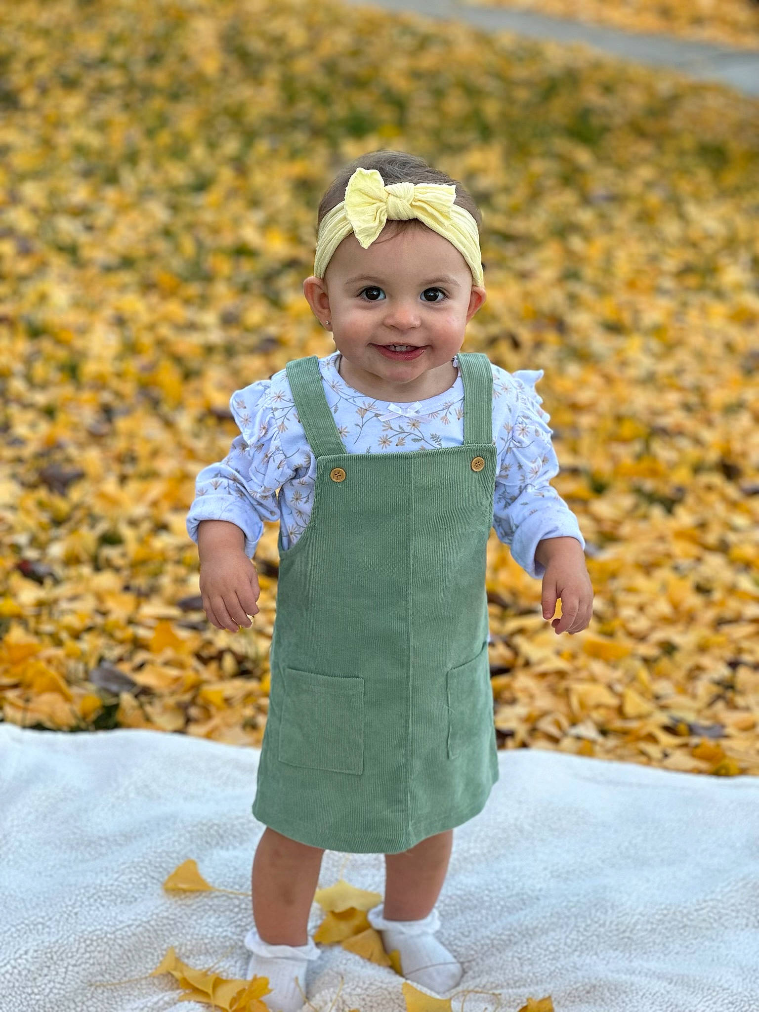 Mia is registered to the contest to win money with this photo: autumn, baby, baby_toddler_clothing, cap, child, face, fashion_accessory, fun, grass, happy, hat, headwear, joy, leaf, outerwear, pattern, people_in_nature, person, play, sleeve