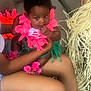 Akiyra joined the competition — help win amazing prizes! baby, child, person, flower_lei, pink, green, couch, sitting, hand, legs, fingers, curly_hair, indoor, decorations, colorful, skin, casual, comfort, closeup, portrait