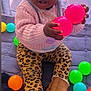 toddler, child, boots, leopard_print, leggings, pink_sweater, colorful_balls, play_mat, indoor, curious, holding, sitting, cute, baby, person, toy, bright_colors, casual_clothing, playing, expression