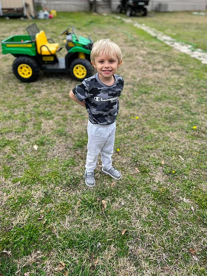 Carter is registered to the contest to win money with this photo: asphalt, automotive_tire, fun, grass, grassland, joy, landscape, lawn, lego, meadow, motor_vehicle, people, people_in_nature, person, recreation, smile, tire, toddler, toy, tread