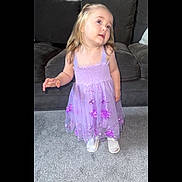 Annie joined the competition — help win amazing prizes! child, girl, purple_dress, floral, carpet, sofa, indoor, blond_hair, smile, curious, person, young, cute, living_room, footwear, white_shoes, standing, portrait, casual, happy