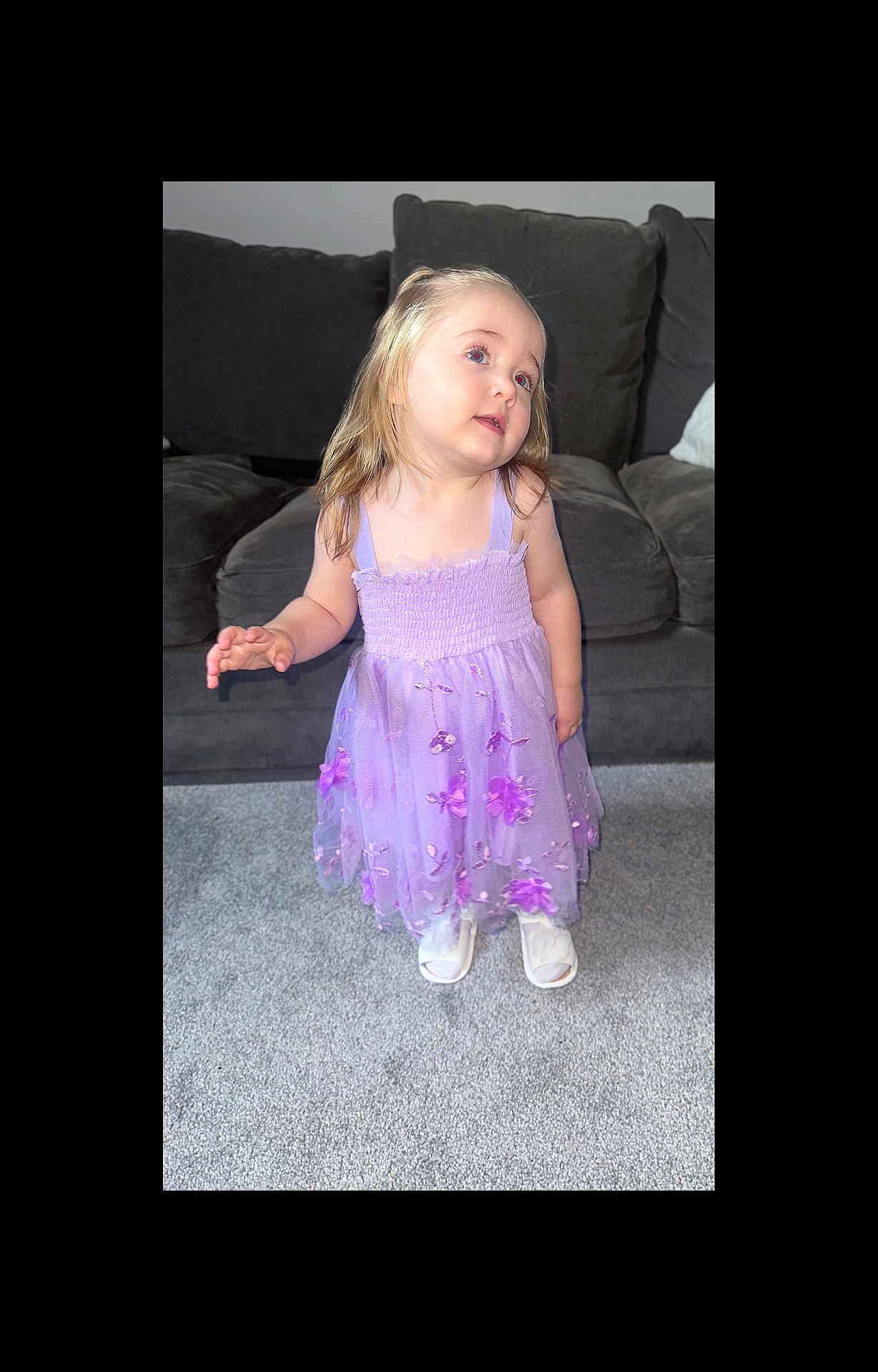 Annie joined the competition — help win amazing prizes! child, girl, purple_dress, floral, carpet, sofa, indoor, blond_hair, smile, curious, person, young, cute, living_room, footwear, white_shoes, standing, portrait, casual, happy
