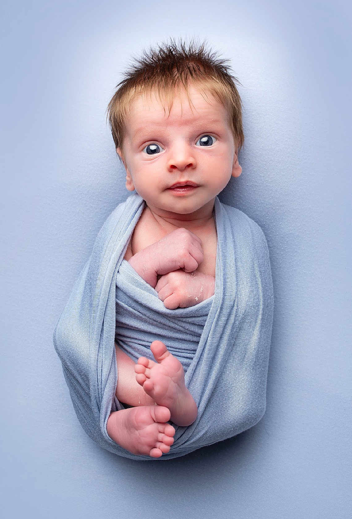 Warren is registered to the contest to win money with this photo: baby, infant, wrapped, blue_blanket, newborn, feet, hands, curious, wide_eyes, soft_texture, portrait, cute, child, studio_lighting, skin, expression, small_toes, cozy, lying_down, human