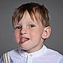 child, boy, tongue_out, white_shirt, suspenders, portrait, playful, light_brown_hair, gray_background, cute, face, head, smiling, studio, expression, casual, young, innocent, funny, closeup