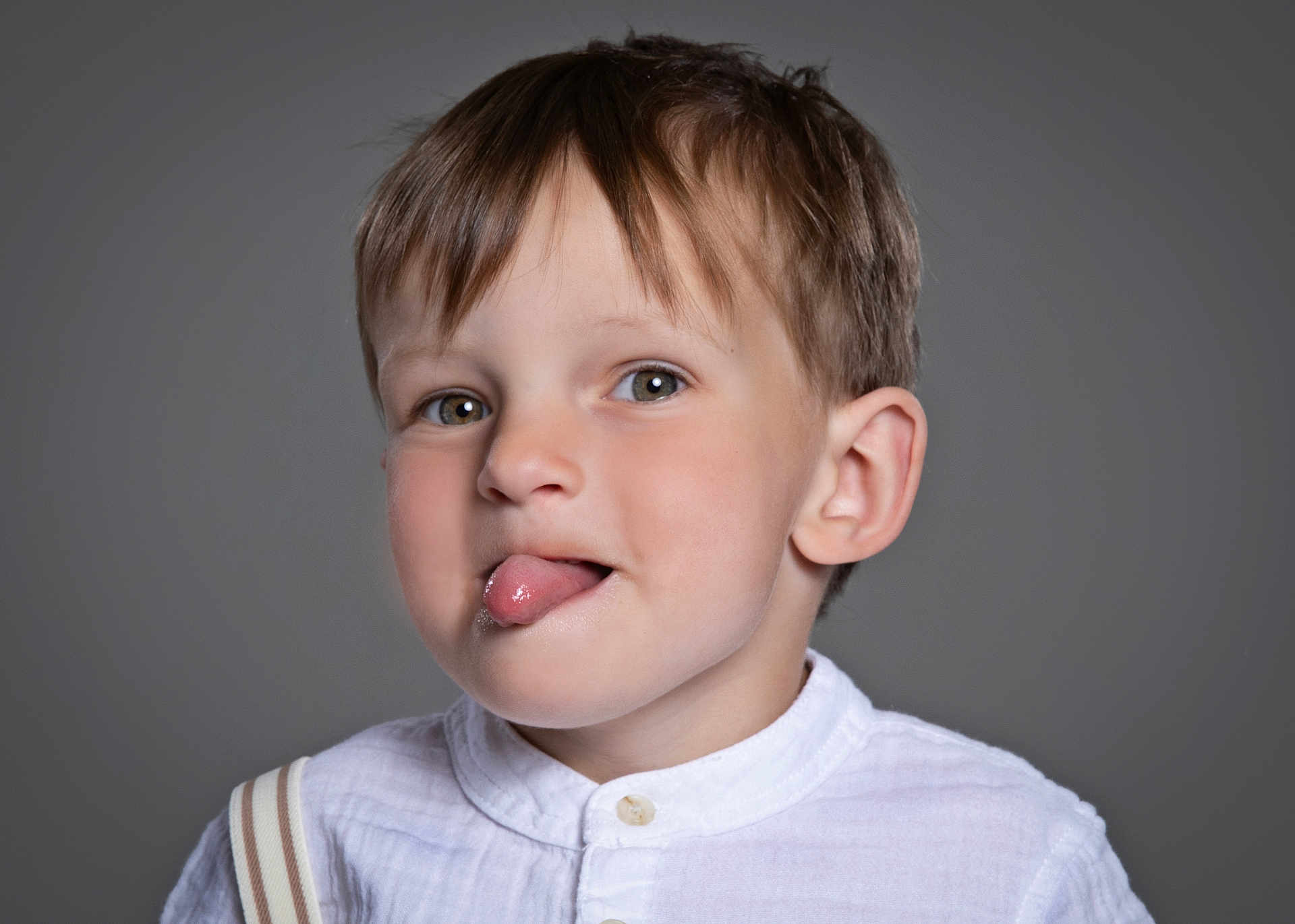Greyson joined the competition — help win amazing prizes! child, boy, tongue_out, white_shirt, suspenders, portrait, playful, light_brown_hair, gray_background, cute, face, head, smiling, studio, expression, casual, young, innocent, funny, closeup