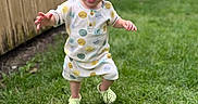 Ronan joined the competition — help win amazing prizes! baby, child, toddler, outdoor, garden, backyard, grass, lawn, smiling, happy, walking, standing, portrait, face, playground, swing_set, wooden_fence, patterned_clothing, shoes, daylight