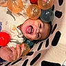 Ronan is registered to the contest to win money with this photo: baby, child, laughing, smiling, face, portrait, playful, indoor, colorful, plastic_balls, ball_pit, cushion, blanket, patterned_fabric, sitting, lying_down, hands, clothing, infant, happy