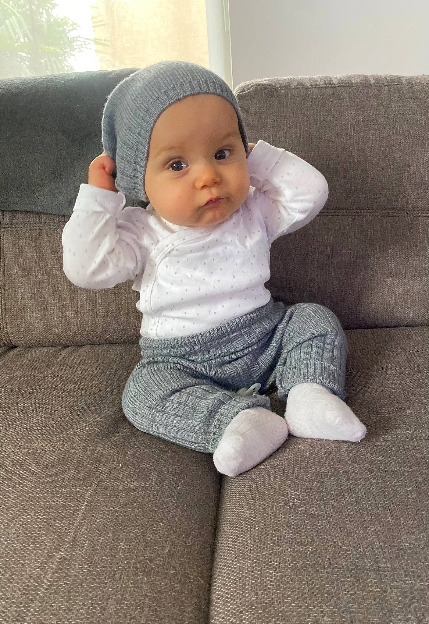Kiki a rejoint le concours — aidez-le/la à gagner de superbes lots ! baby, baby_products, baby_sleeping, baby_toddler_clothing, beanie, cap, cheek, child, comfort, fashion_accessory, flooring, fur, headwear, knit_cap, leg, linens, person, sitting, sleeve, toddler