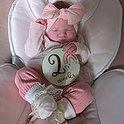 Evelyn joined the competition — help win amazing prizes! baby, newborn, infant, sleeping, pink_clothing, headband, bow, milestone_sign, two_weeks, baby_seat, soft_fabric, cute, peaceful, small_hands, white_socks, lace, portrait, indoors, child, resting