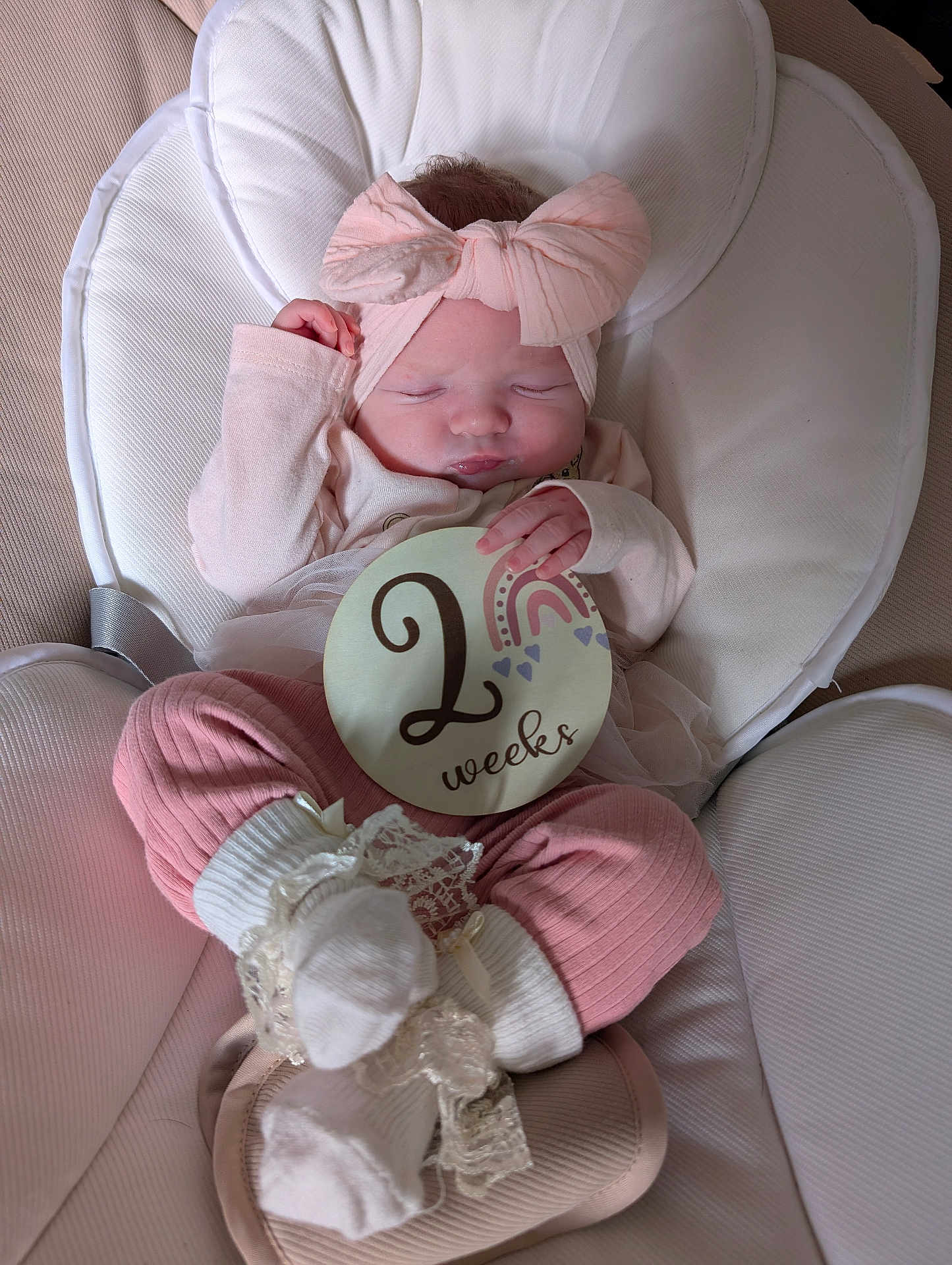 Evelyn joined the competition — help win amazing prizes! baby, newborn, infant, sleeping, pink_clothing, headband, bow, milestone_sign, two_weeks, baby_seat, soft_fabric, cute, peaceful, small_hands, white_socks, lace, portrait, indoors, child, resting