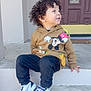 toddler, child, curly_hair, hoodie, mickey_mouse, sneakers, puma, pants, sitting, concrete, steps, outdoor, door, smiling, casual_clothing, side_view, young_child, person, daylight, happy
