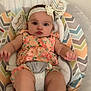 Isabella is registered to the contest to win money with this photo: baby, infant, child, baby_seat, floral_outfit, headband, flower, patterned_cushion, indoor, curious_expression, pursed_lips, wide_eyes, soft_fabric, child_seat, cute, baby_girl, colorful, comfort, relaxed, seated