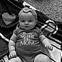 baby, infant, onesie, headband, bow, blanket, carpet, pattern, text_on_clothing, cute, chubby, lying_down, indoors, soft_texture, child, portrait, smiling, happy, skin, toddler