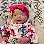 Thea is registered to the contest to win money with this photo: baby, baby_chair, butterfly_pattern, child, comfort, cozy, cute, dress, fabric, headband, indoor, infant, patterned_clothing, person, pink, playful, seat, smile, soft, toddler