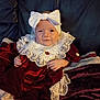 baby, child, portrait, dress, bow, velvet, lace, red, white, couch, leather, smile, sitting, indoor, cute, hands, feet, headwear, person, infant