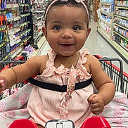 Jaionna is registered to the contest to win money with this photo: baby, child, shopping_cart, headband, pink, flower, store_aisle, retail, smile, face, person, clothing, sitting, grocery_store, shopping, infant, cute, happy, toddler, indoor