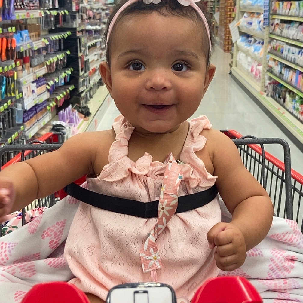Jaionna is registered to the contest to win money with this photo: baby, child, clothing, cute, face, flower, grocery_store, happy, headband, indoor, infant, person, pink, retail, shopping, shopping_cart, sitting, smile, store_aisle, toddler