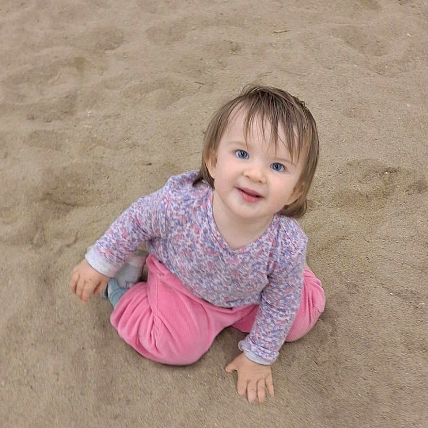 Charlee-Jo joined the competition — help win amazing prizes! toddler, child, sand, outdoor, happy, smiling, blue_eyes, pink_pants, patterned_shirt, sitting, playful, hair, face, casual_clothing, nature, young_child, cute, joyful, baby, portrait