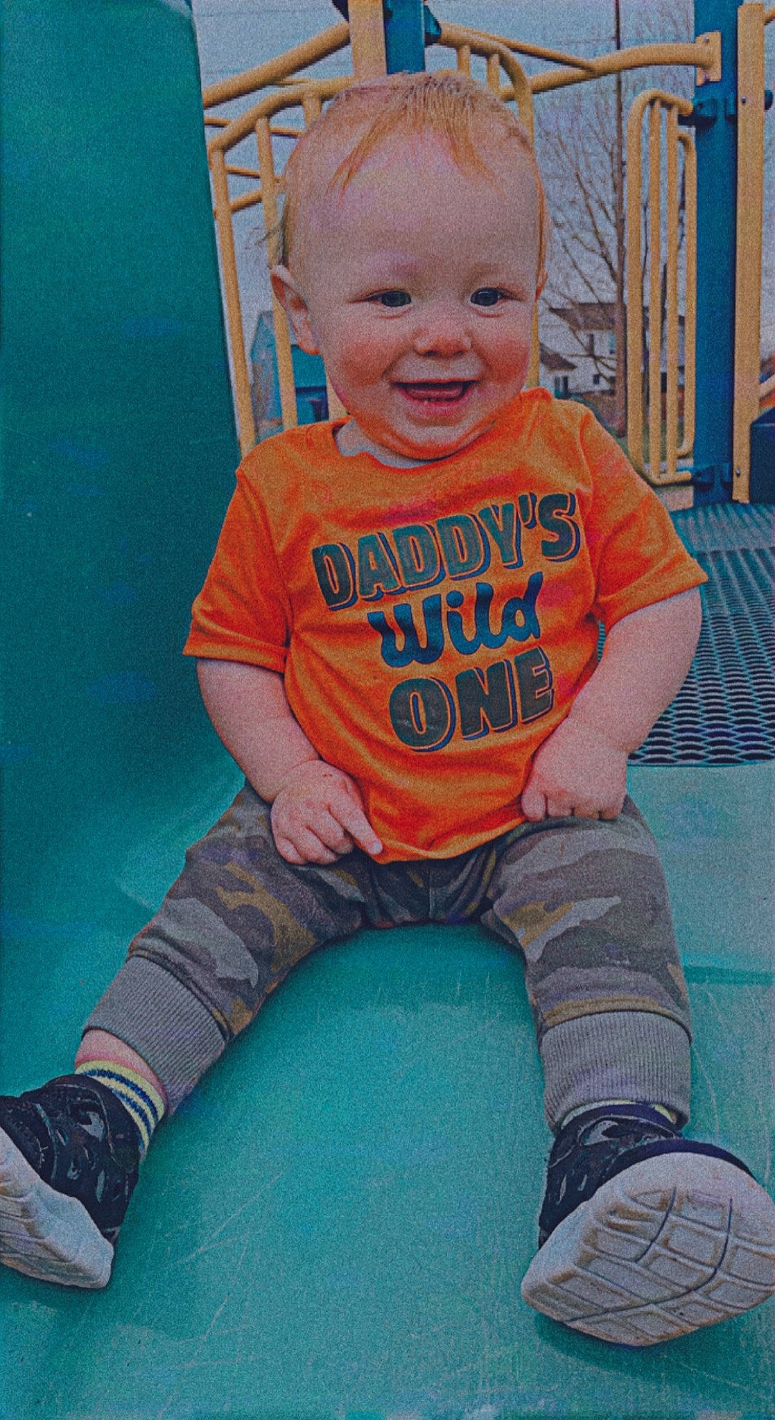 Axel is registered to the contest to win money with this photo: baby_toddler_clothing, blue, chair, eye, face, facial_expression, fun, green, happy, leg, orange, person, photograph, pink, shoe, skin, sleeve, smile, standing, t_shirt