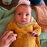 Charlotte joined the competition — help win amazing prizes! baby, infant, hand, knitted_clothing, yellow_sweater, bow, headband, blanket, bottle, baby_wipes, person, skin, face, eyes, mouth, hands, soft_texture, indoor, nursery, cute