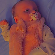 Charlotte is registered to the contest to win money with this photo: baby, pacifier, pink_vest, clothing, infant, lying_down, soft_texture, face, hand, sleeve, cute, sleepy, child, portrait, rest, indoor, fabric, warm_clothing, newborn, comfort