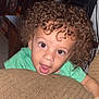 Camari joined the competition — help win amazing prizes! child, toddler, curly_hair, green_shirt, couch, indoor, face, wide_eyes, open_mouth, curious, living_room, furniture, cushion, brown, skin, person, young, expression, hair, smiling