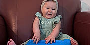 Xanova joined the competition — help win amazing prizes! baby, child, headband, green_dress, tablet_case, blue, brown_chair, leather, smiling, happy, sitting, indoors, cute, hands, feet, wall, light_switch, portrait, playful, young_child