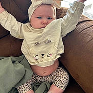 Xanova joined the competition — help win amazing prizes! baby, infant, child, headband, bow, sweater, cat_face, leopard_print, leggings, socks, couch, blanket, furniture, indoors, person, cute, chubby, stretching, expression, portrait