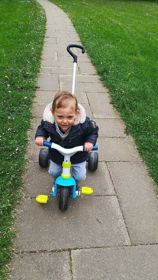 Hugo a rejoint le concours — aidez-le/la à gagner de superbes lots ! child, fun, grass, lawn, person, play, riding_toy, toddler, tricycle, vehicle, wheel