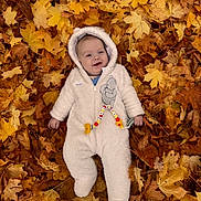 Elliott is registered to the contest to win money with this photo: baby, child, autumn, fall_leaves, leaves, outdoor, onesie, hooded_clothing, smiling, cute, infant, lying_down, seasonal, nature, playful, warm_clothing, person, forest_floor, happy, winnie_the_pooh
