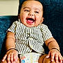 baby, blue_couch, bright, child, couch, cute, diaper, face, hands, happy, indoor, infant, joyful, person, plump_arms, portrait, sitting, smiling, striped_shirt, young_child