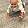 Gian is registered to the contest to win money with this photo: baby, child, crawling, cute, expression, eyes, floor, happy, head, indoor, long_sleeve, pants, person, playful, skin, small_hands, smile, striped_shirt, wooden_floor, young_child