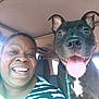 person, dog, car_interior, smiling, tongue_out, black_dog, seat, collar, leash, happy, indoor, head, face, pet, companion, close_up, striped_shirt, window, daylight, friendship