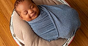 Kyrie joined the competition — help win amazing prizes! baby, sleeping, wrapped, blanket, blue, cushion, beige, bucket, wooden_floor, infant, peaceful, cozy, portrait, indoor, newborn, smiling, child, head, face, resting