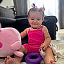 baby, child, pink_outfit, pink_bows, pacifier, purple_ring, blue_ring, toy, play_mat, indoor, living_room, couch, curtains, smiling, happy, sitting, foot, hair, necklace, soft_toys