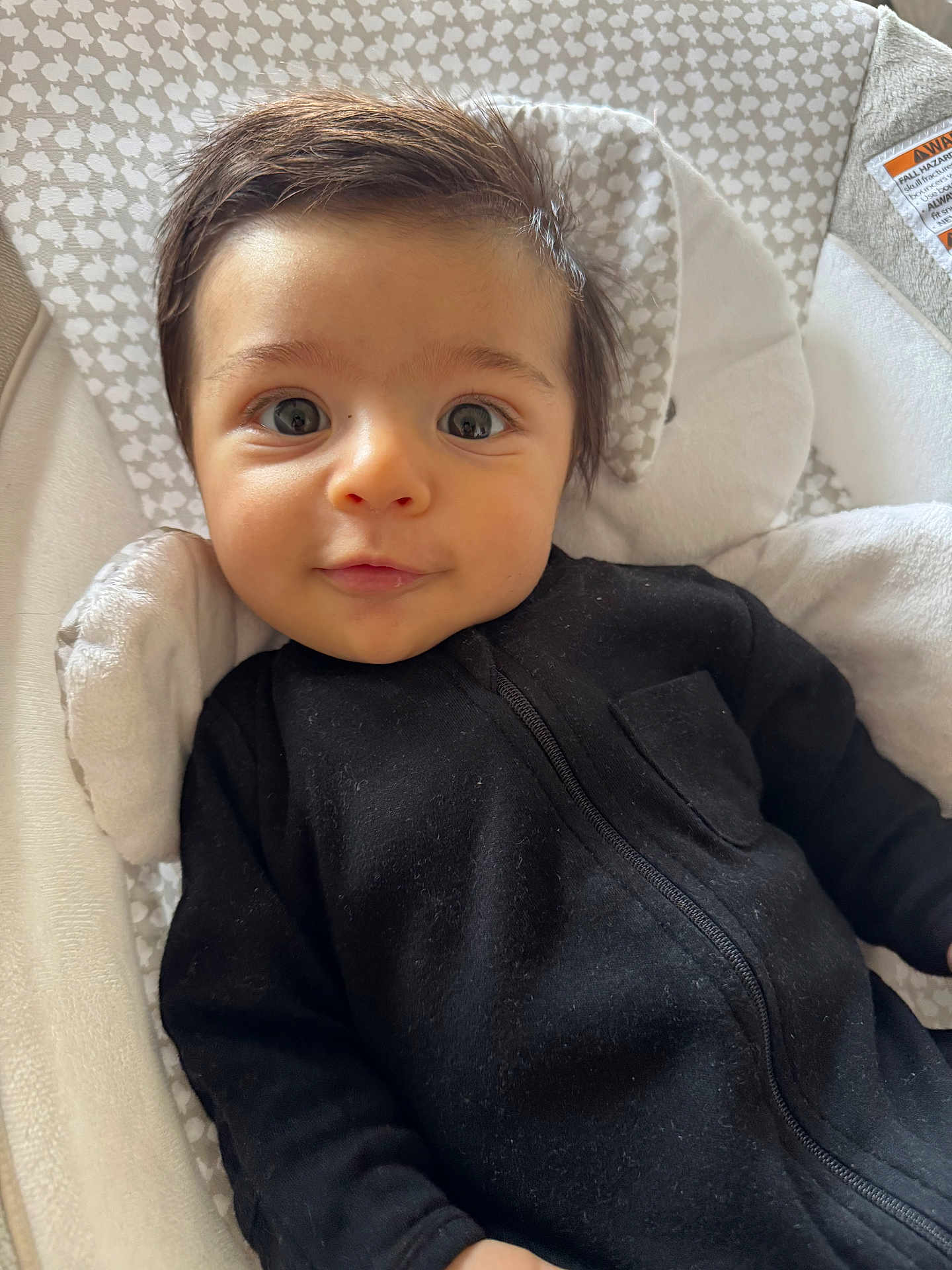 Davi joined the competition — help win amazing prizes! baby, infant, face, eyes, black_clothing, baby_seat, cushion, patterned_background, smile, indoor, young_child, cute, portrait, child, cozy, soft_lighting, person, closeup, head, expression